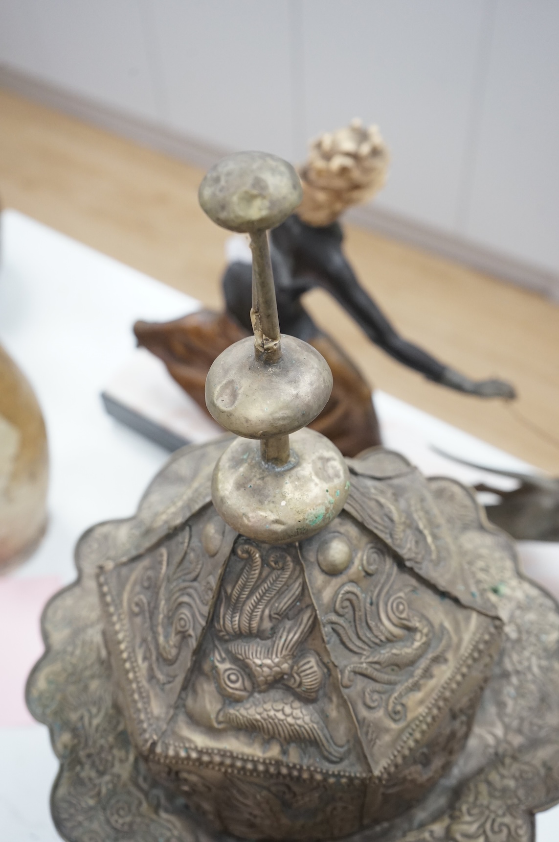 A Chinese Miao tribe embossed metal ceremonial headdress on stand, 63cm high